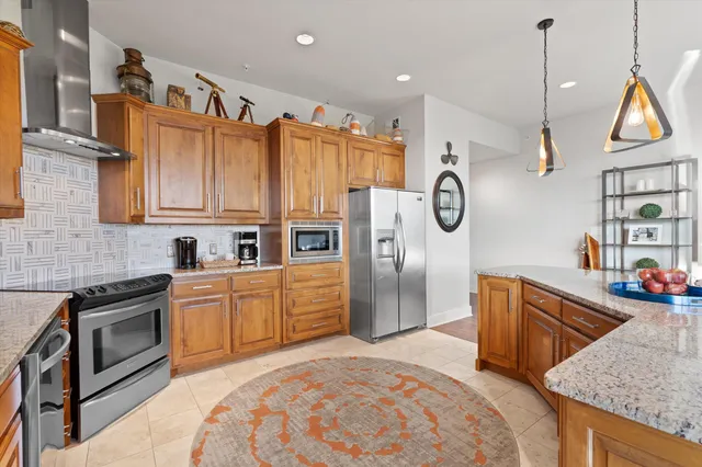 a kitchen with stainless steel appliances granite countertop a refrigerator a sink dishwasher and wooden cabinets with wooden floor