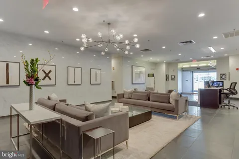 a living room with furniture kitchen view and a chandelier