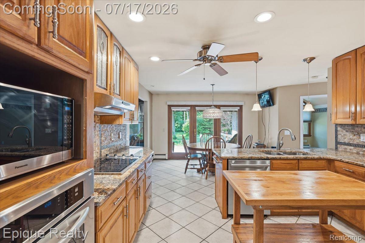 22520 Waltz Road New Boston, MI 48164 - Photo 18 of 43 Kitchen featuring wood cabinetry, granite countertops, tile flooring, built-in stainless steel appliances, and a glass-paneled door leading to an outdoor area