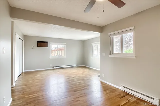 an empty room with wooden floor and windows