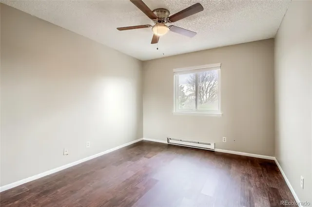 an empty room with wooden floor ceiling fan and windows