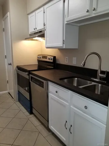 a kitchen with granite countertop white cabinets and black appliances