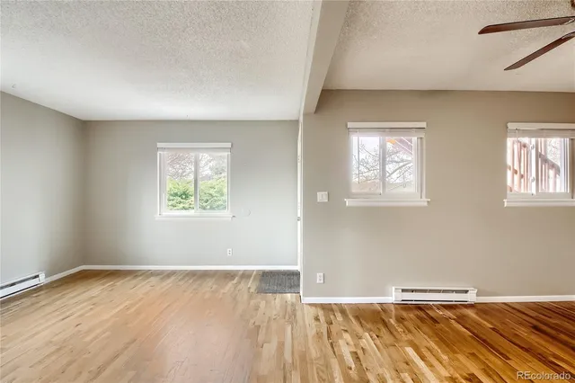 an empty room with wooden floor and windows