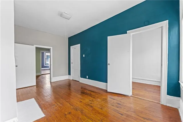 a view of an empty room with wooden floor and closet