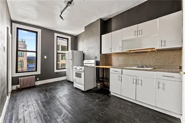 a kitchen with granite countertop a sink cabinets and wooden floor