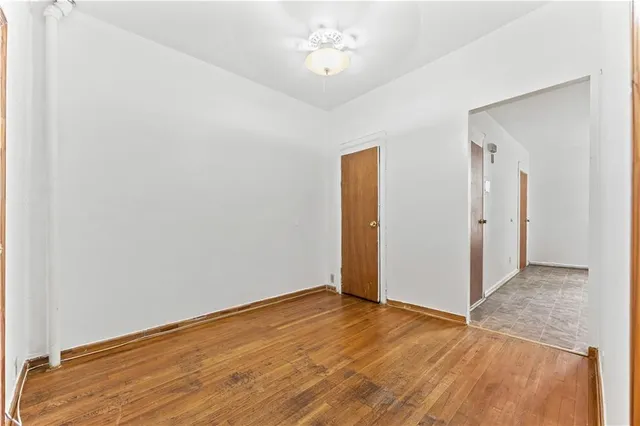 an empty room with wooden floor and a ceiling fan