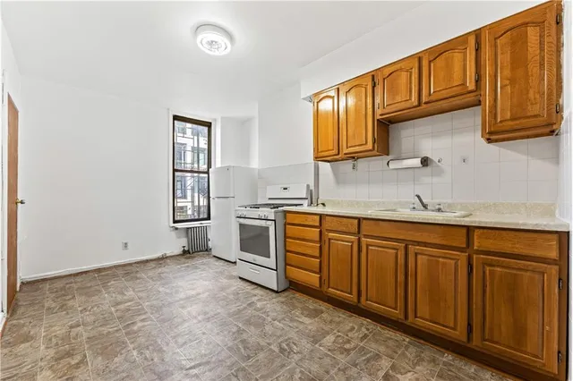 a kitchen with granite countertop a sink cabinets stainless steel appliances and a window