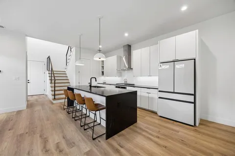 a kitchen with stainless steel appliances granite countertop a refrigerator a stove a sink dishwasher and a dining table with wooden floor
