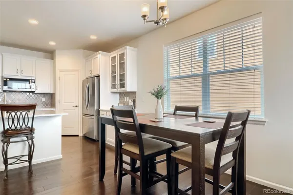 a dining room with stainless steel appliances kitchen island granite countertop a dining table chairs and a refrigerator