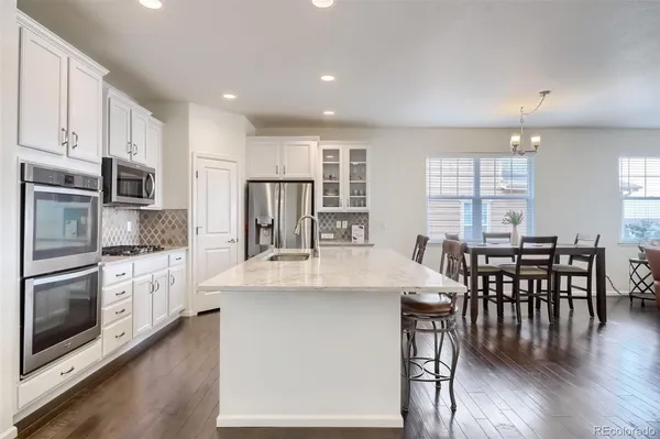 a kitchen with stainless steel appliances granite countertop a stove a sink a microwave a center island and chairs