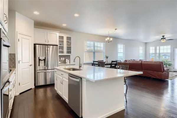 a large kitchen with stainless steel appliances a refrigerator a sink dishwasher a stove and white cabinets with wooden floor