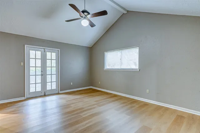 an empty room with wooden floor fan and windows