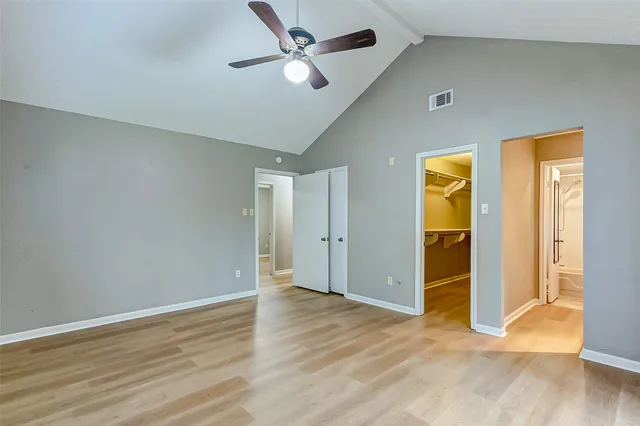 an empty room with wooden floor and a ceiling fan