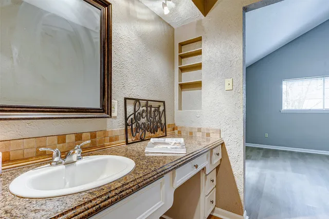 a bathroom with a granite countertop sink and a mirror