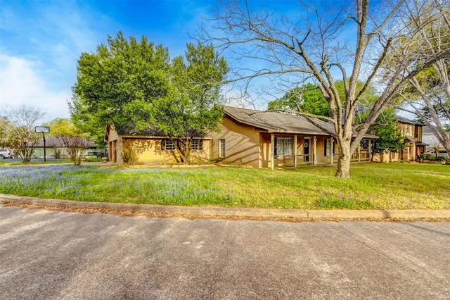 a view of a house with a big yard plants and large trees