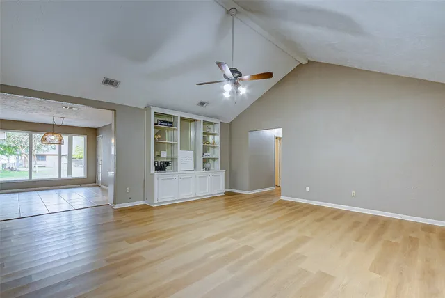 a view of an empty room with a window and wooden floor