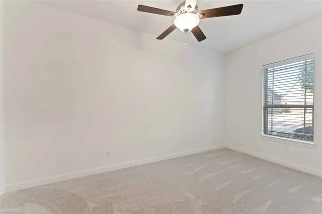 an empty room with a window and a fan