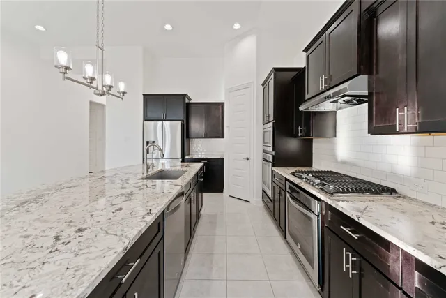 a kitchen with stainless steel appliances granite countertop a sink a stove and a refrigerator