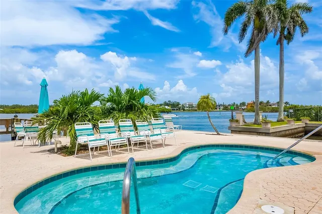 a view of a swimming pool with a lawn chairs under palm trees