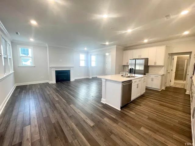 a large white kitchen with kitchen island a sink wooden floor and a refrigerator