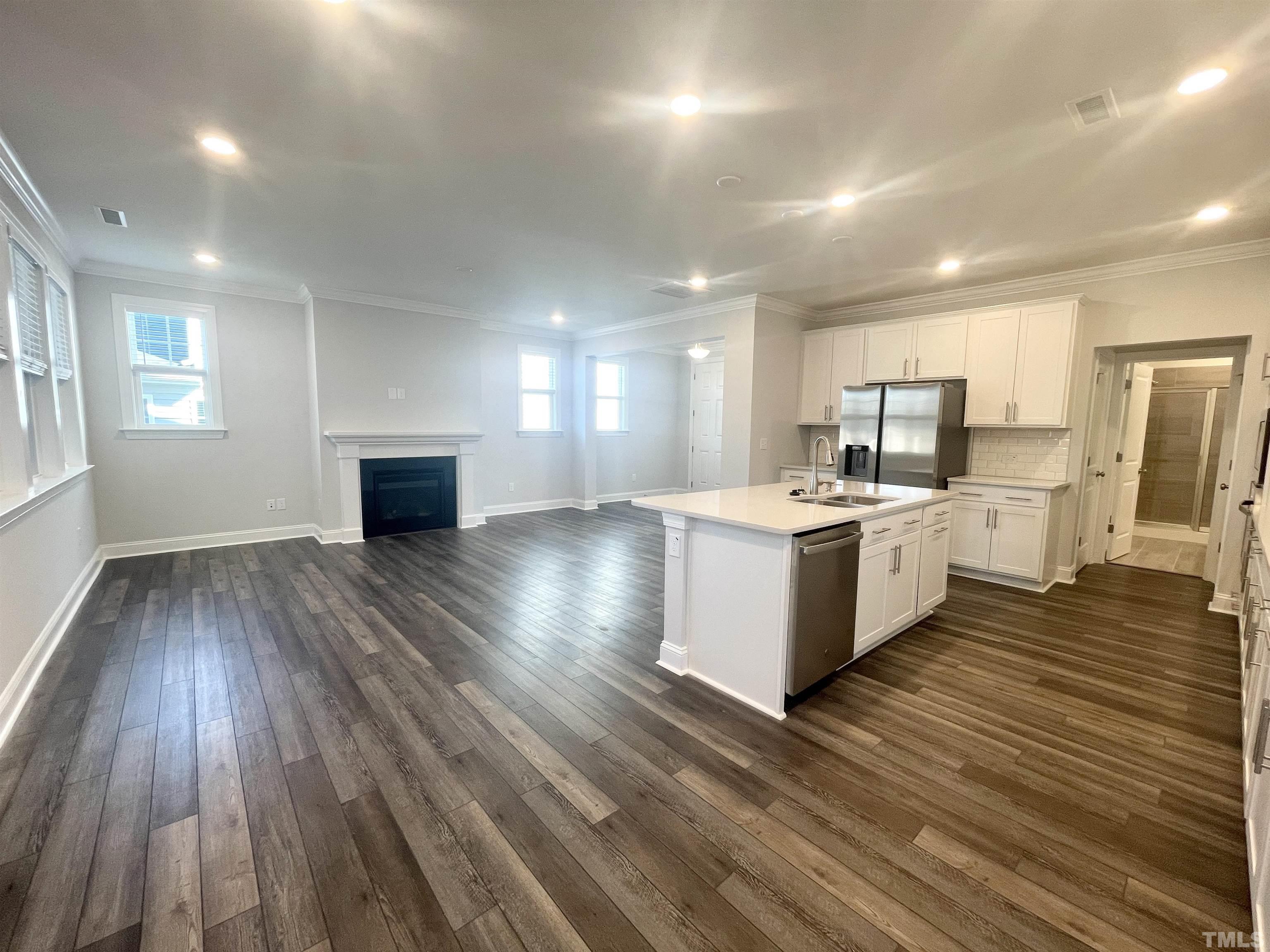 191 Edge Of Auburn Boulevard Raleigh, NC 27610 - Photo 4 of 24 a large white kitchen with kitchen island a sink wooden floor and a refrigerator