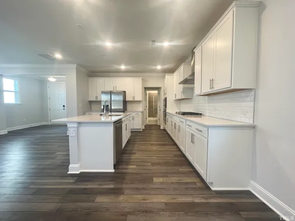 a large white kitchen with kitchen island a sink a center island stainless steel appliances and a counter top space