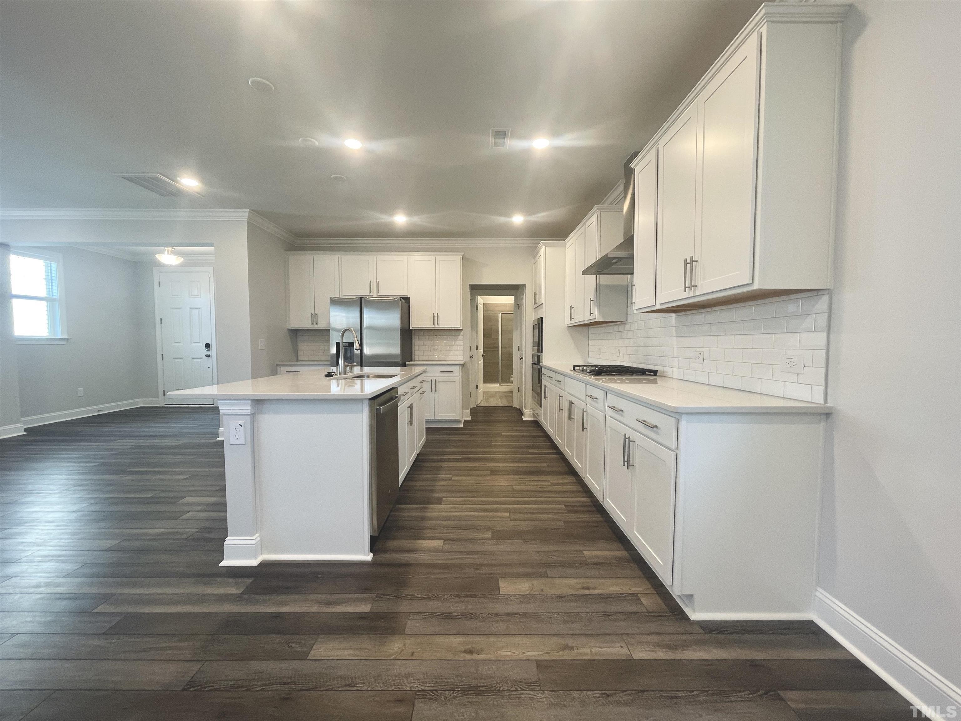 191 Edge Of Auburn Boulevard Raleigh, NC 27610 - Photo 6 of 24 a large white kitchen with kitchen island a sink a center island stainless steel appliances and a counter top space