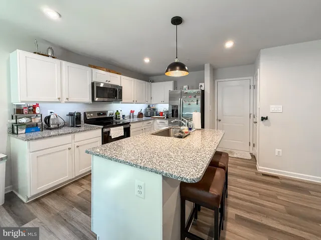 a kitchen with stainless steel appliances granite countertop a sink dishwasher a stove refrigerator and cabinets with wooden floor