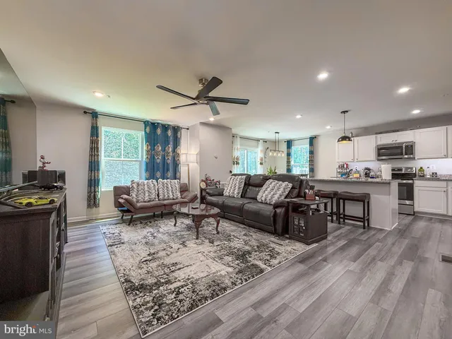 a living room with furniture kitchen view and a wooden floor