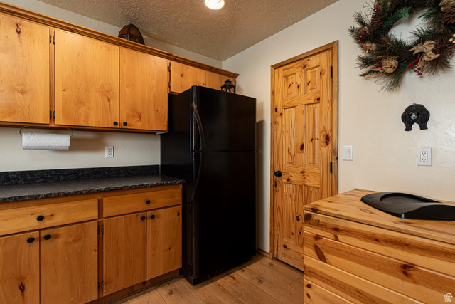 1505 West Elk Ridge Drive Alton, UT 84710 - Photo 38 of 53 Kitchen featuring dark countertops, a textured ceiling, freestanding refrigerator, light wood finished floors, and brown cabinets