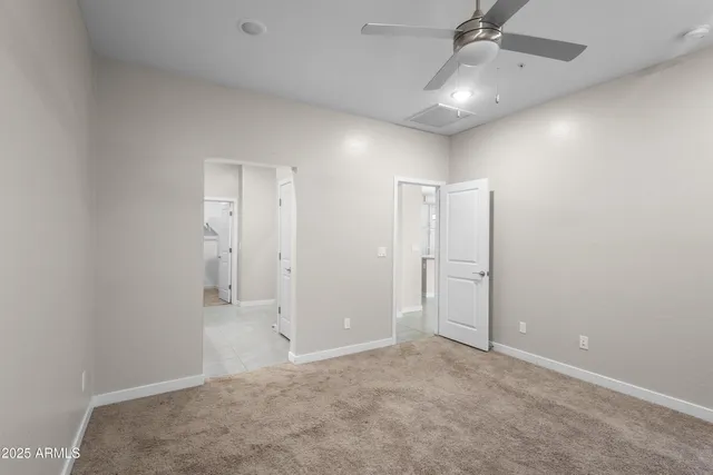 an empty room with chandelier fan and windows