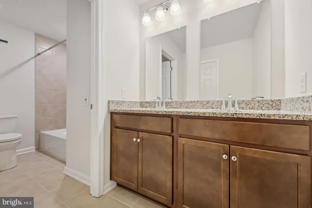 a bathroom with a granite countertop sink a toilet and mirror