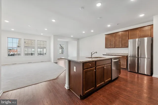 a kitchen with stainless steel appliances granite countertop a refrigerator a sink dishwasher and a oven with wooden floors