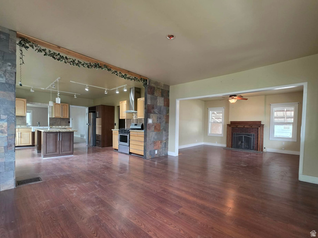 250 South Main Street Fillmore, UT 84631 - Photo 2 of 12 Unfurnished living room with dark wood finished floors, a fireplace, rail lighting, and a ceiling fan
