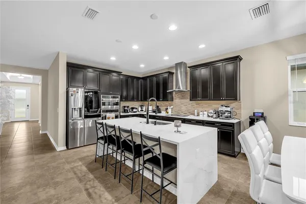 a kitchen with appliances a refrigerator and chairs