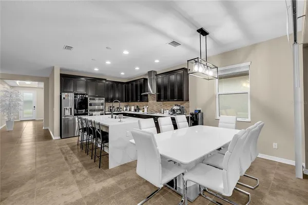 a living room with couches a kitchen view and a refrigerator with wooden floor