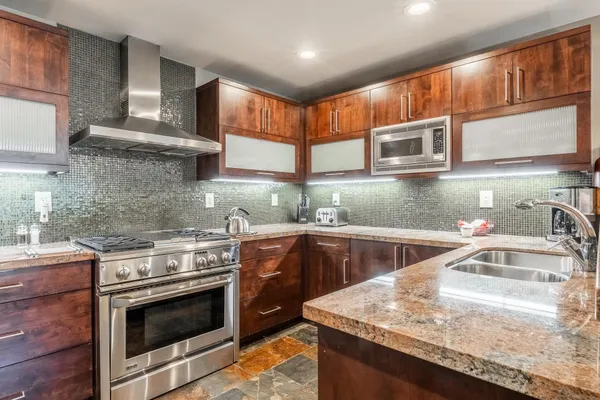 a kitchen with stainless steel appliances granite countertop a sink stove and cabinets