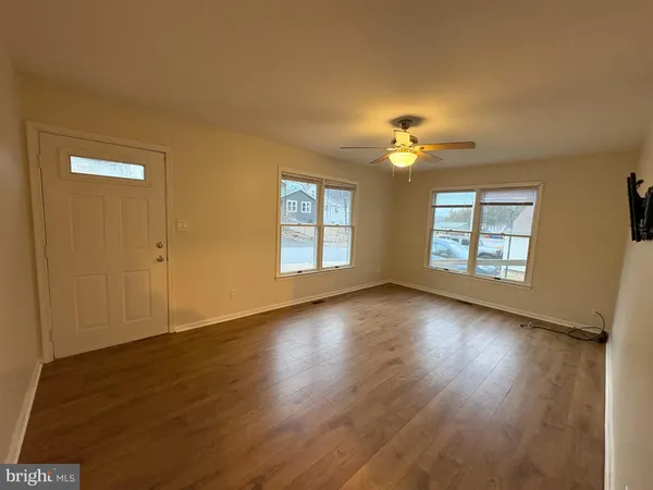 a view of an empty room with a window and wooden floor