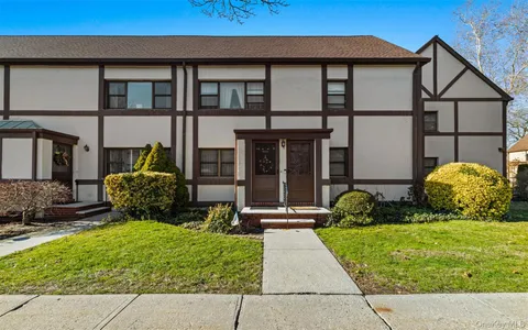 a view of a brick house with potted plants and a yard
