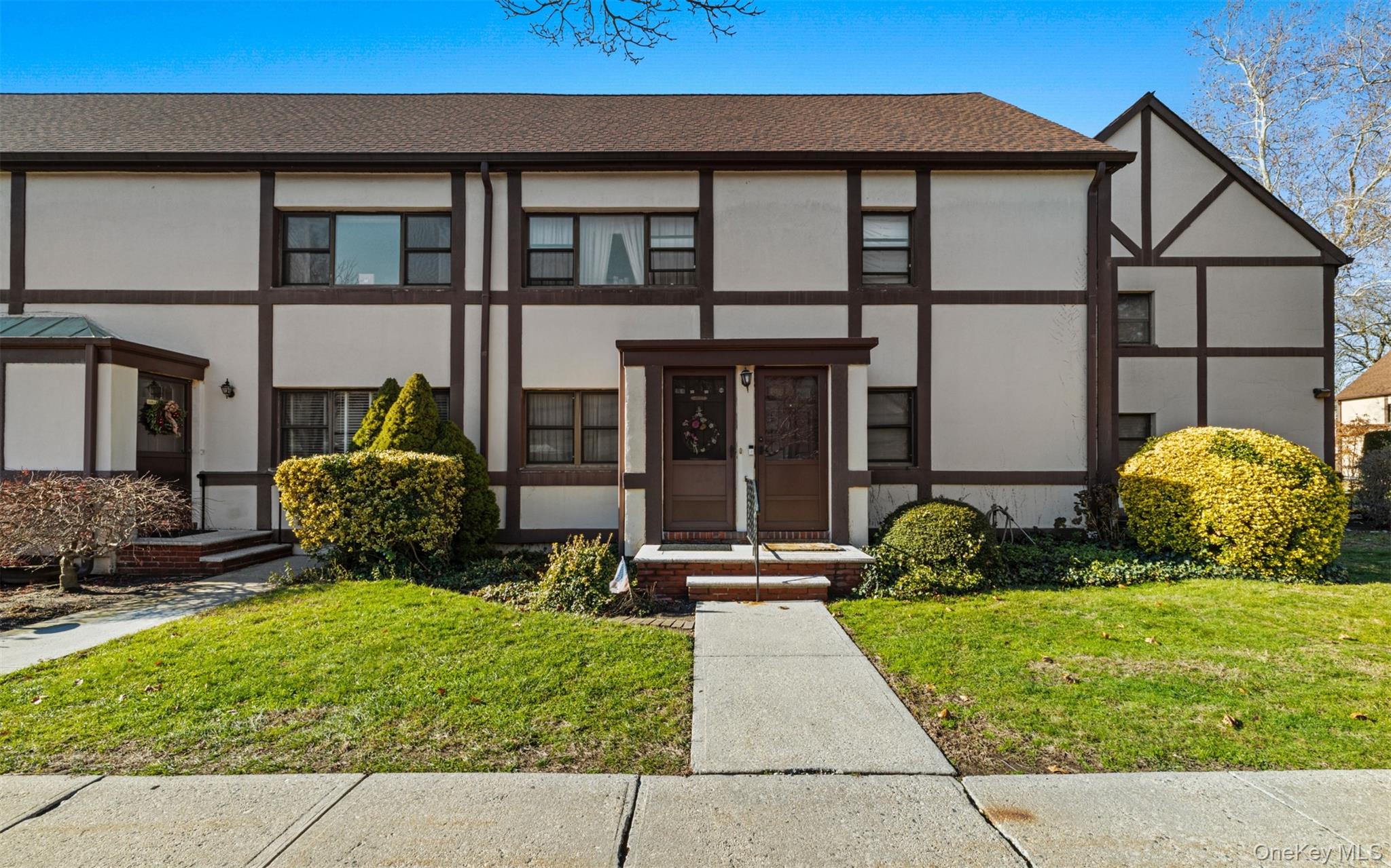 113 15th Street, Unit 1C Garden City, NY 11530 - Photo 3 of 14 a view of a brick house with potted plants and a yard