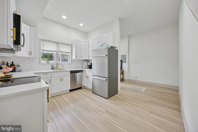 a kitchen with a sink a refrigerator and white cabinets