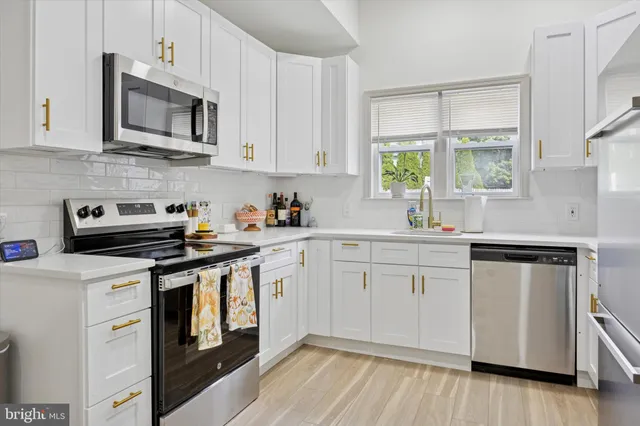 a kitchen with cabinets appliances a sink and a window