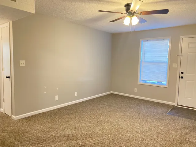 an empty room with windows and fan