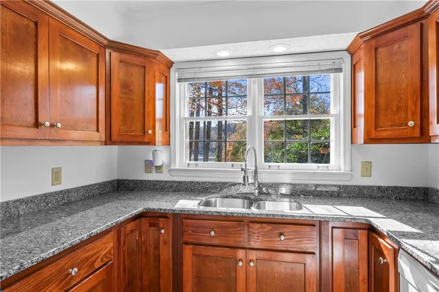 a kitchen with granite countertop a sink window and cabinets