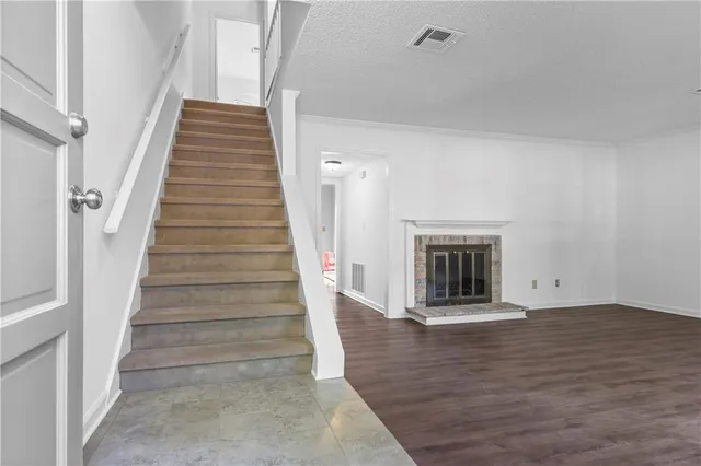 a view of an empty room with wooden floor and fireplace