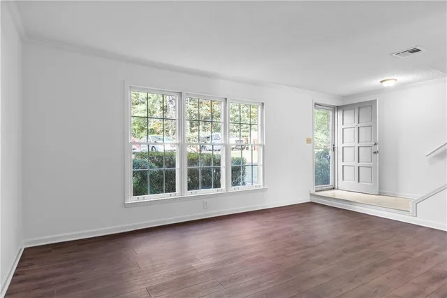 an empty room with wooden floor and windows