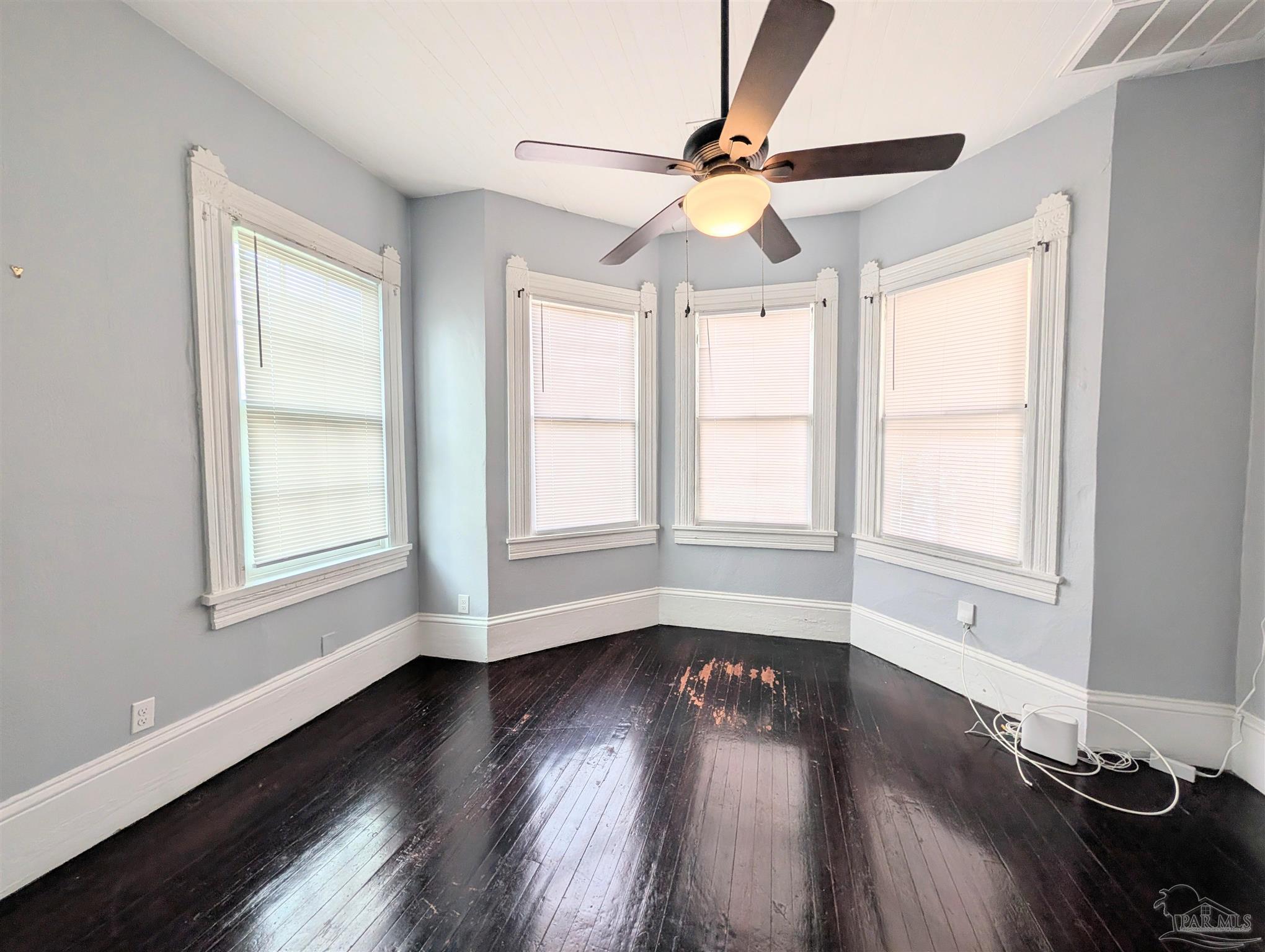 911 North Spring Street, Unit 4 Pensacola, FL 32501 - Photo 7 of 16 an empty room with wooden floor fan and windows