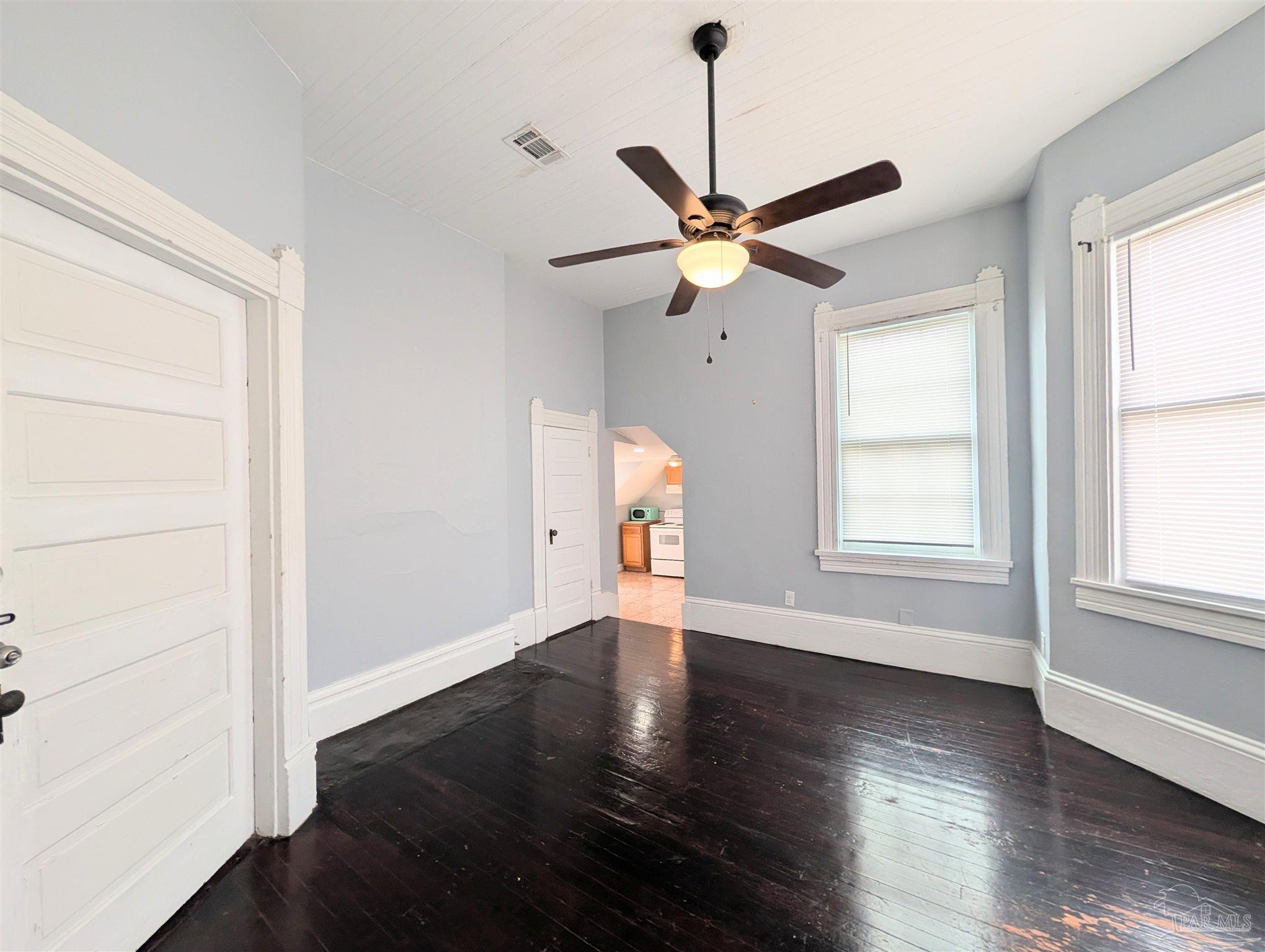 911 North Spring Street, Unit 4 Pensacola, FL 32501 - Photo 8 of 16 an empty room with wooden floor fan and windows