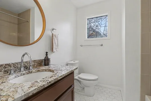 a bathroom with a granite countertop sink a toilet and a mirror