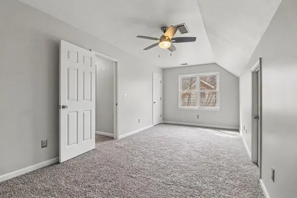 an empty room with windows and fan